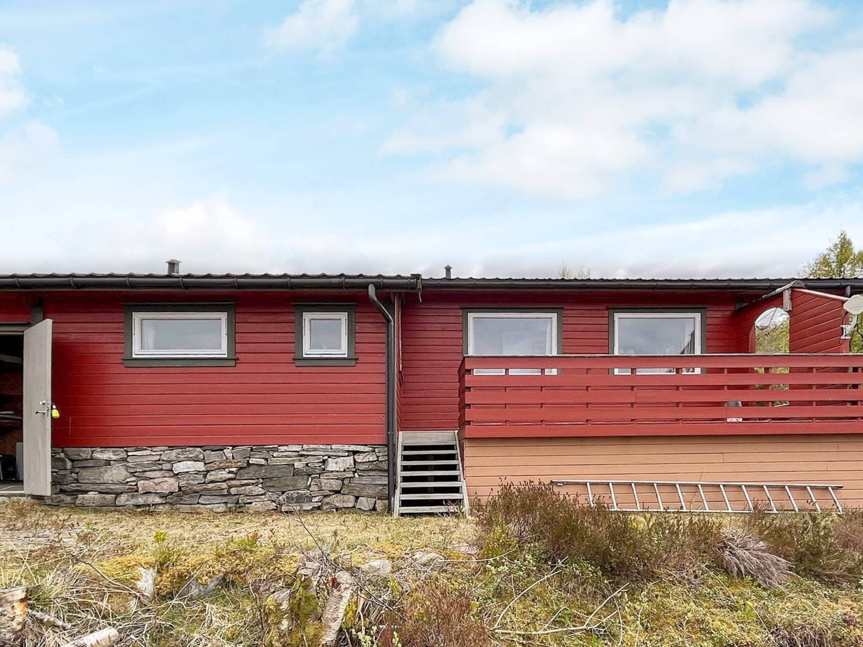 A red building with a stone foundation and a wooden deck.