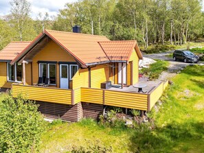 A yellow cabin with a red roof, wooden deck, and a small outdoor seating area. - 6 Person Holiday Home in Anneland (Gulen)
