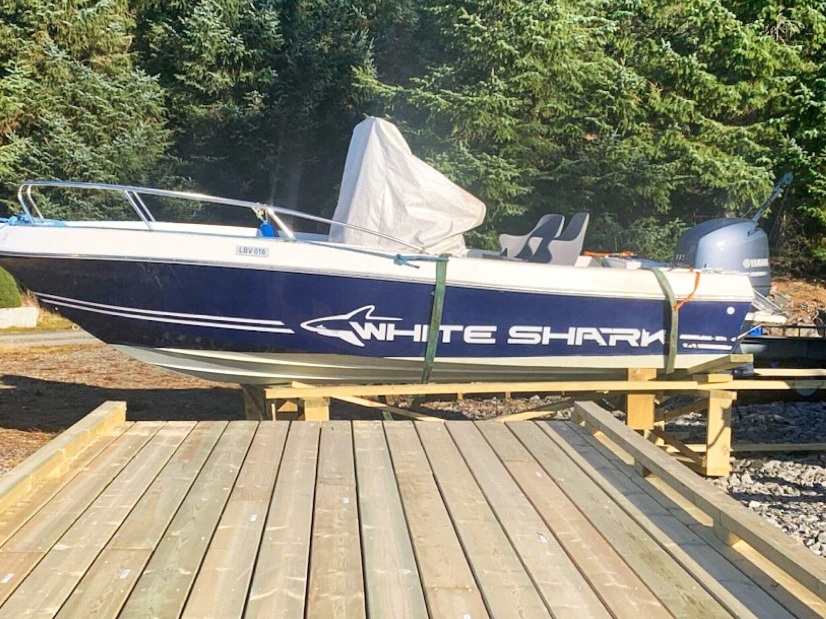 Un bateau portant le nom « WHITE SHARK » sur sa coque était amarré à un quai en bois.