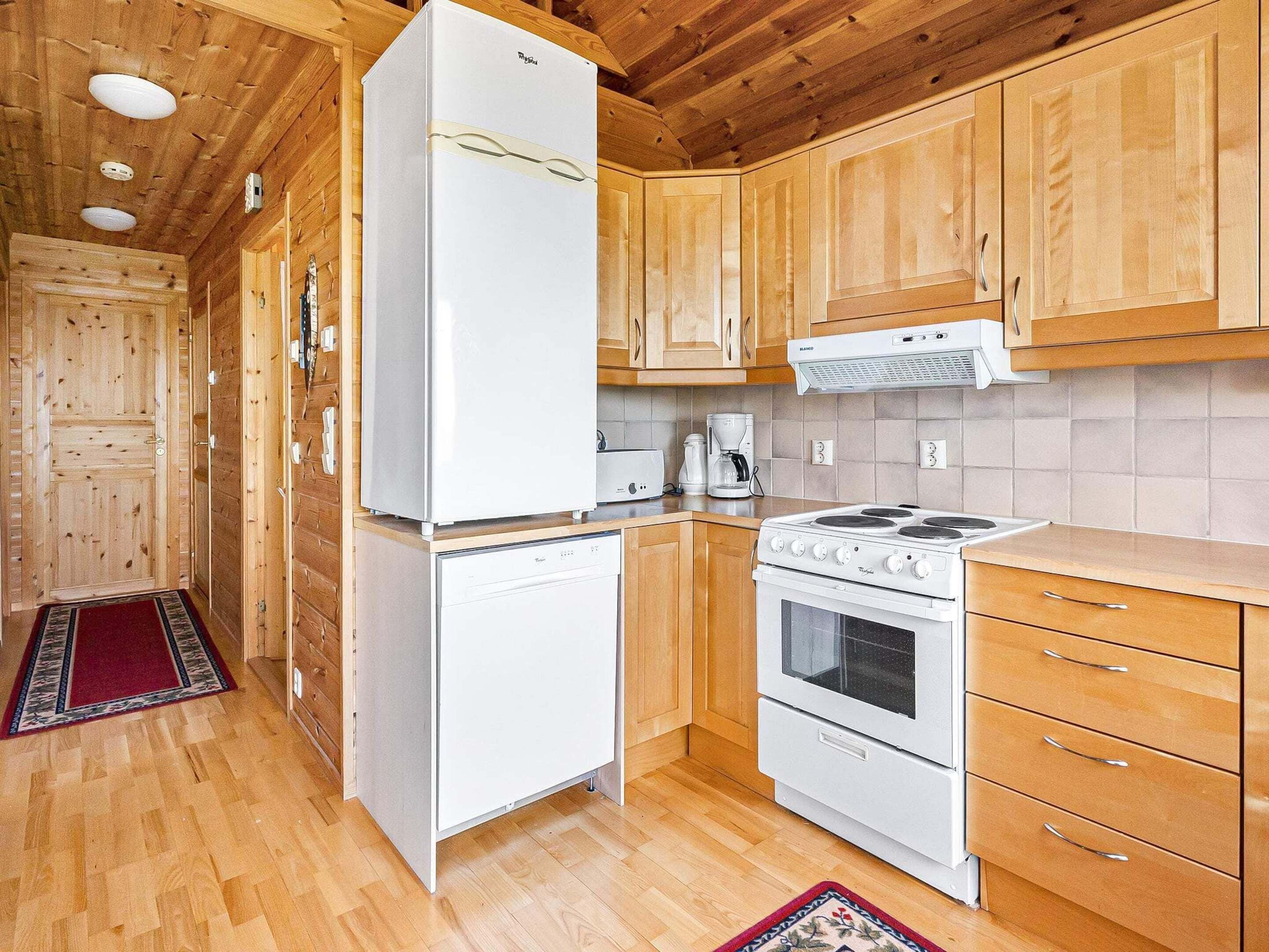 A compact kitchen with wooden cabinets, a white refrigerator, a stove, and a coffee maker.