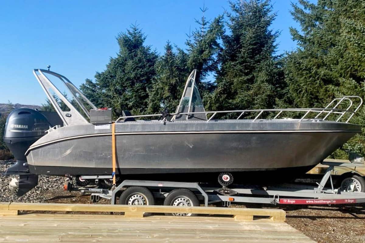 A small motorboat on a trailer with a Yamaha outboard motor, surrounded by trees.