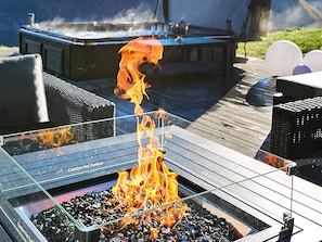 A barbecue grill with flames, surrounded by outdoor furniture and a hot tub. - 8 Person Holiday Home in Valldal (Fjord)