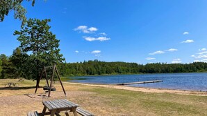 A lakeside park with picnic tables and a swing set. - 5 Person Holiday Home in Morlunda (Mörlunda)