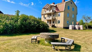A two-story building with a balcony, a stone table, and a picnic table in a grassy area. - 5 Person Holiday Home in Morlunda (Mörlunda)