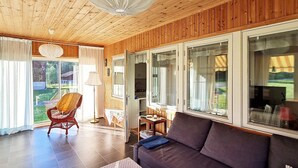A cozy living room with a wooden ceiling, a sofa, a chair, and a table.