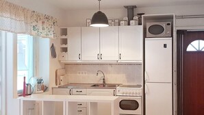 A compact kitchen with white cabinets, a built-in oven, a microwave, and a sink.