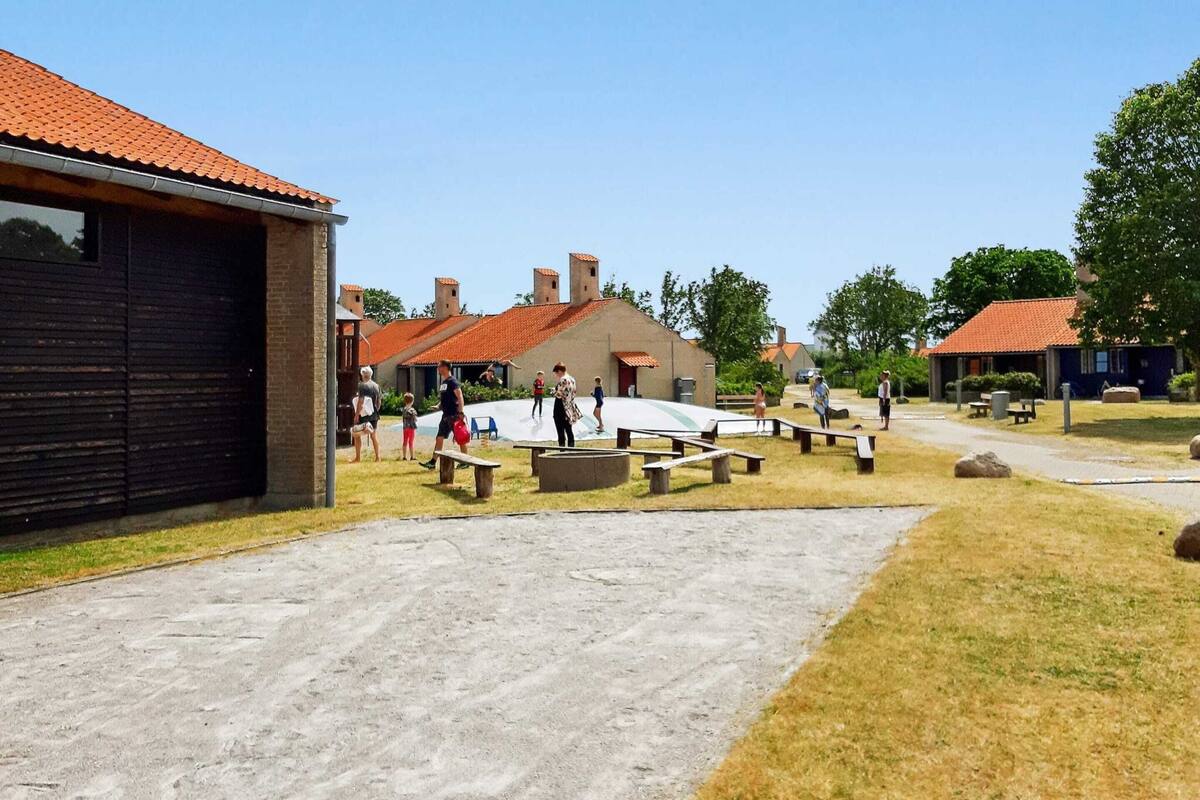 A courtyard with picnic tables, a playground, and a building with a red-tiled roof.