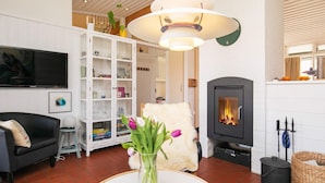 A living room with a fireplace, a white cabinet, a black sofa, and a TV mounted on the wall.