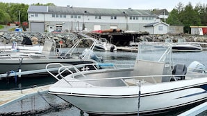 A marina with several boats docked, a stone wall, and a building in the background. - 4 Person Holiday Home in Oksvoll (Orland)