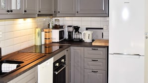 A kitchen with grey cabinets, a white refrigerator, a microwave, a coffee maker, and a wooden countertop. - 4 Person Holiday Home in Oksvoll (Orland)