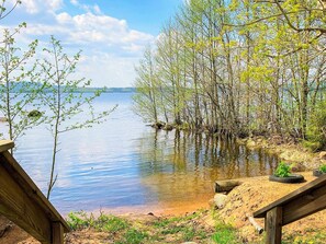 A lakeside view with a wooden deck and a sandy area with tire planters. - 4 Person Holiday Home in Braas (Braås)