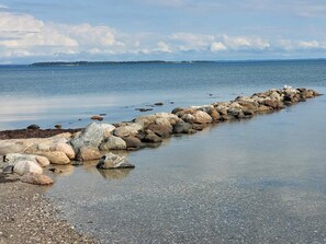 A rocky shoreline with a calm sea and distant land. - 2 Person Holiday Home in Hejls (Hejls)