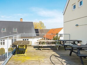 Eine Holzterrasse mit Picknicktischen und einem Metallgeländer.