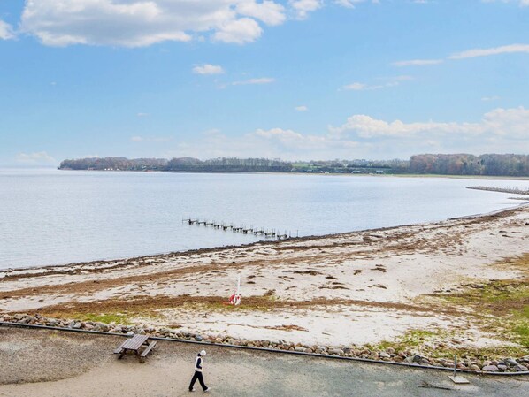 Ein Sandstrand mit einer Holzpromenade und einer Person, die darauf geht.