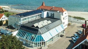 Un hotel moderno con un invernadero de vidrio, una piscina y vistas al mar.