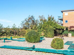 Ein Innenhof mit grünen Bänken, einem kleinen Garten und einem Gebäude mit Balkon.