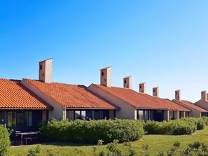 A row of modern buildings with red-tiled roofs and brick walls, surrounded by green shrubbery. - 6 Person Holiday Home on a Holiday Park in Saeby (Sæby)