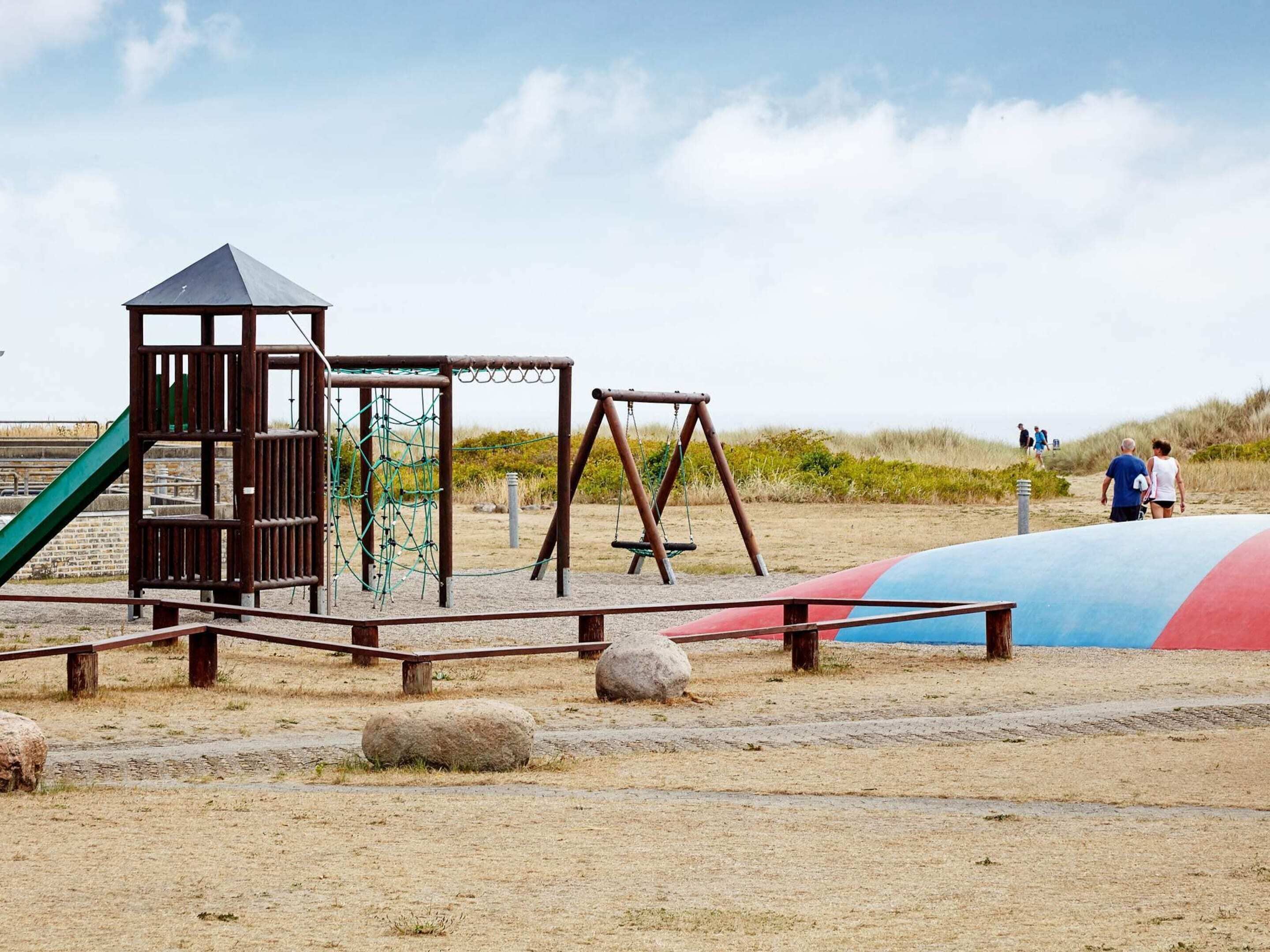 A playground with a climbing structure, swings, and a slide.