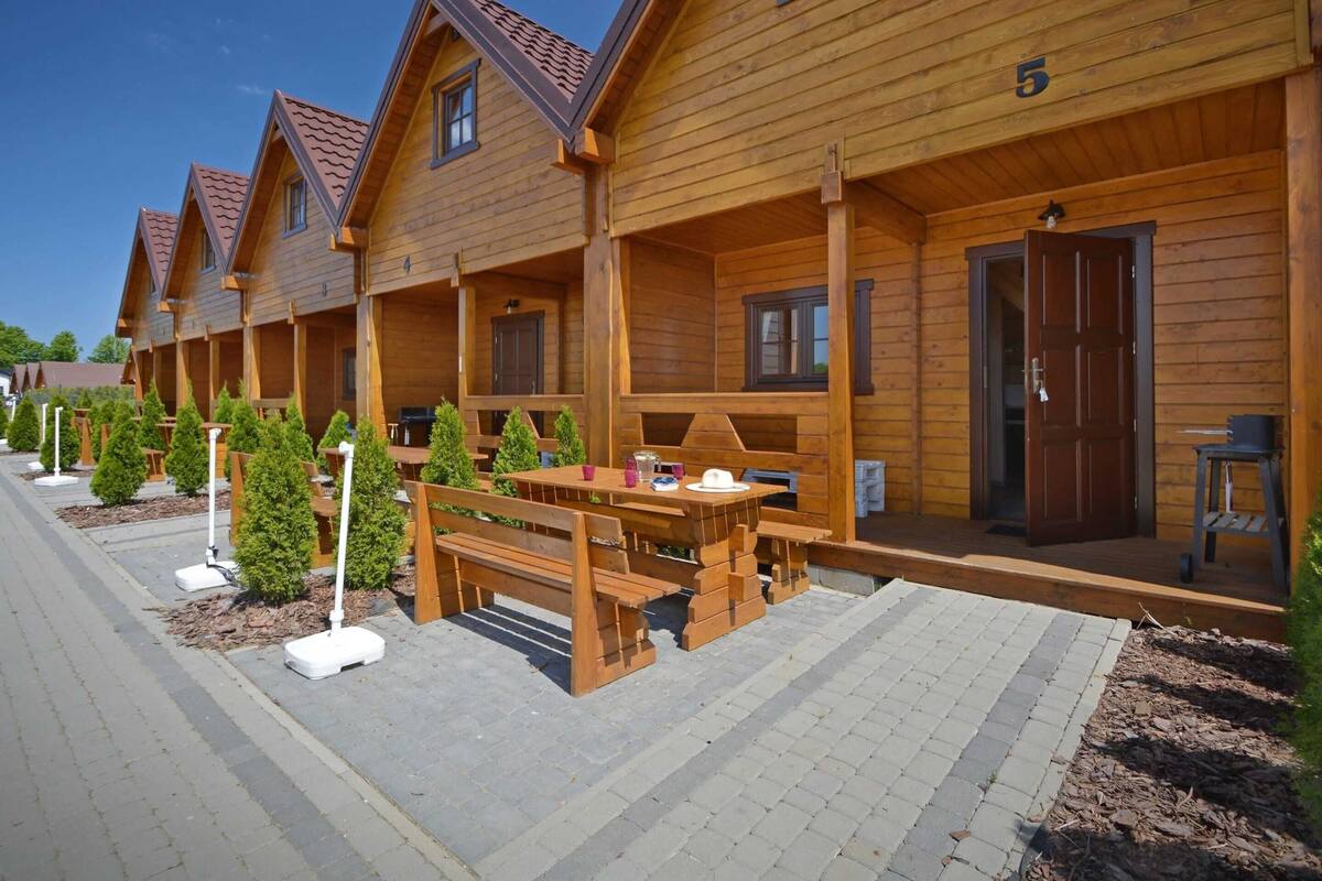 Une rangée de cabanes en bois, dotées d’une terrasse couverte, chacune ayant une porte et des fenêtres.