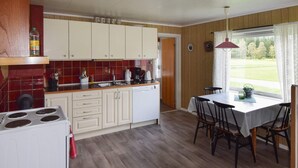 A compact kitchen with a stove, cabinets, and a dining area with a table and chairs. - 8 Person Holiday Home in Terrak (Bindal)