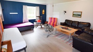A modern living room with a sofa, a coffee table, a rocking chair, and a bed. - 8 Person Holiday Home in Terrak (Bindal)