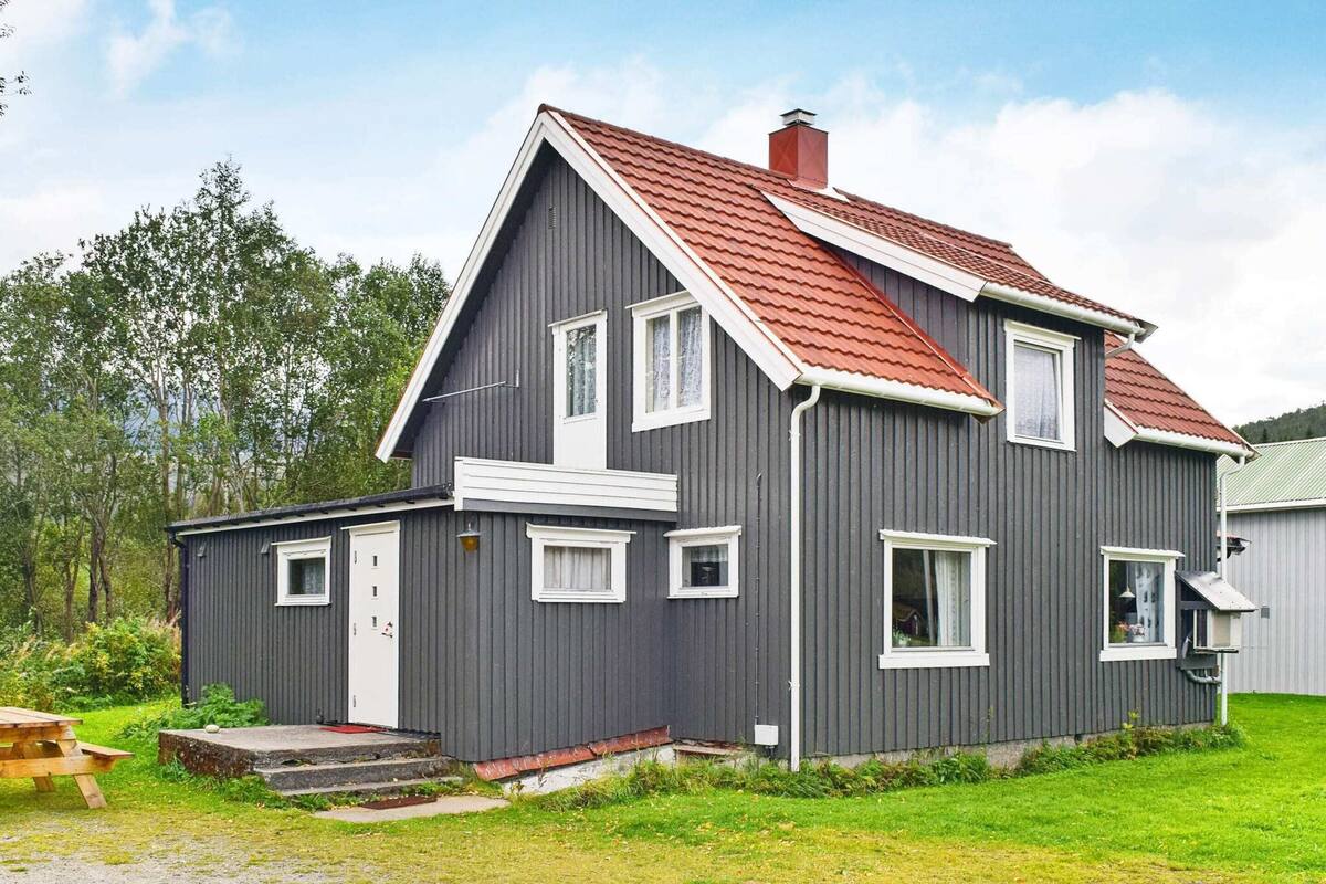 A two-story house with a red roof, grey siding, and white trim.