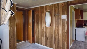 A room with wooden panel walls, a mirror, a white door, and a kitchen area visible through an open doorway. - 8 Person Holiday Home in Terrak (Bindal)