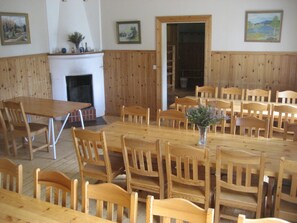 A dining area with wooden tables and chairs, a fireplace, and framed artwork on the walls.