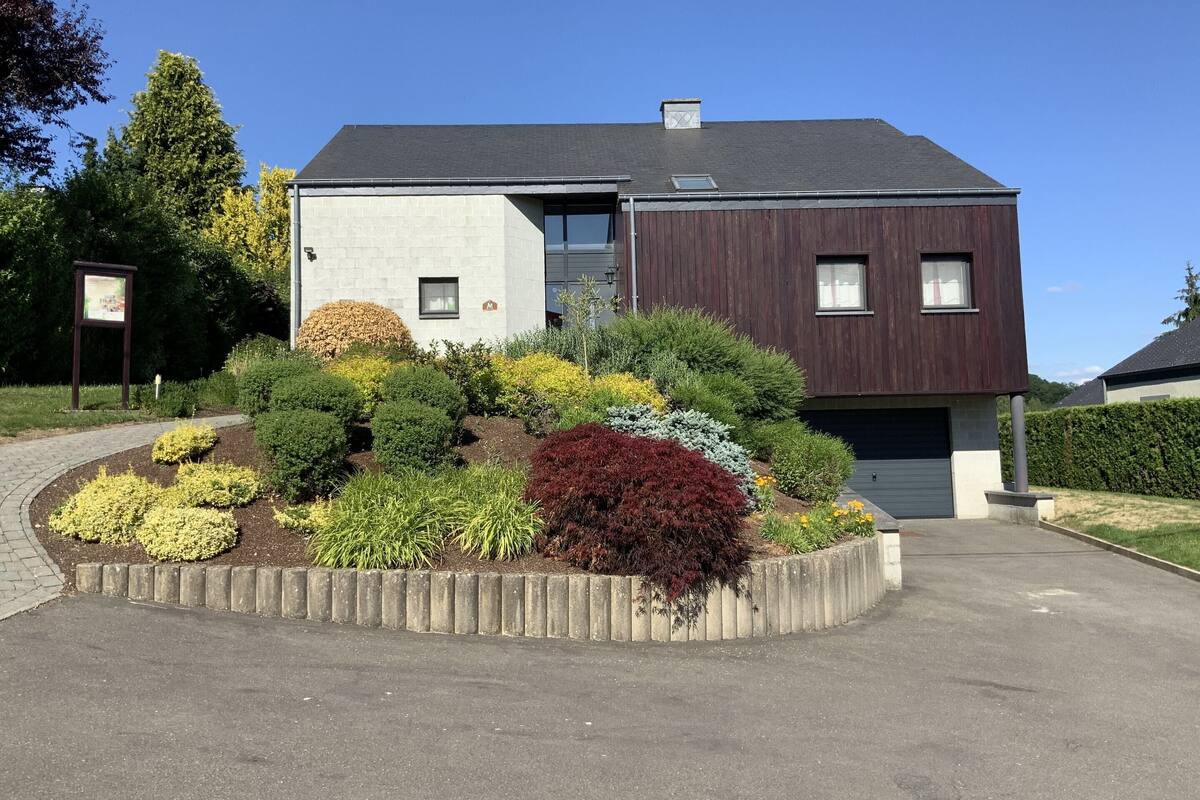 A modern two-story house with a landscaped garden in front.