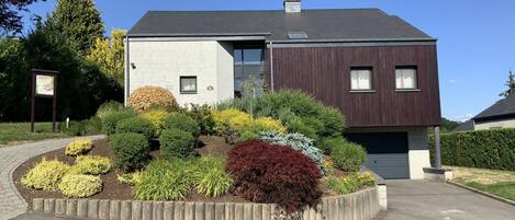 A modern two-story house with a landscaped garden in front.