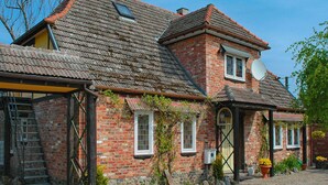 A traditional brick house with a sloped roof, a satellite dish, and a small garden area with potted plants. - Stylish House in the Countryside 5 km From the sea (Darlowo)