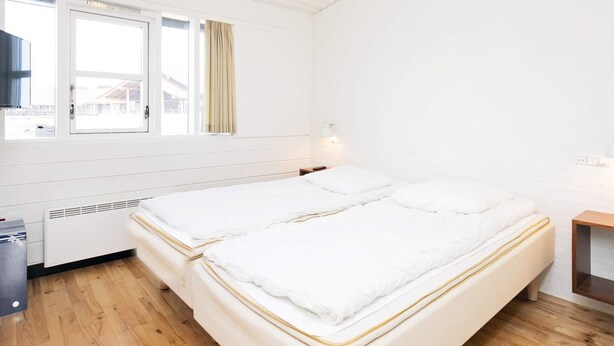 A room with two beds, a window, a heater, and a small table.