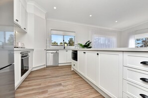 A modern kitchen with white cabinetry, a dishwasher, a stove, and a microwave.