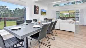 Un espace de restauration moderne, doté d’une grande table, de chaises et offrant une vue sur l’extérieur.