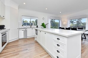 A modern kitchen with white cabinetry, a central island, and a view of the outdoors.