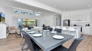 Een moderne eetruimte met een lange tafel voor zes personen, omringd door stoelen.