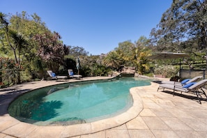 A swimming pool with lounge chairs and a shaded area, surrounded by trees and greenery. - The Valley Way Luxury Estate (Mardi)