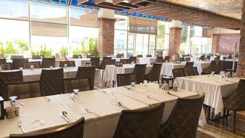 Un restaurante con varias mesas, cada una con manteles blancos y sillas marrones.