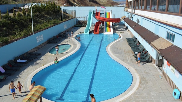 A swimming pool with a slide, lounge chairs, and a small kiddie pool. - Koç Otel Çankırı (Cankiri)