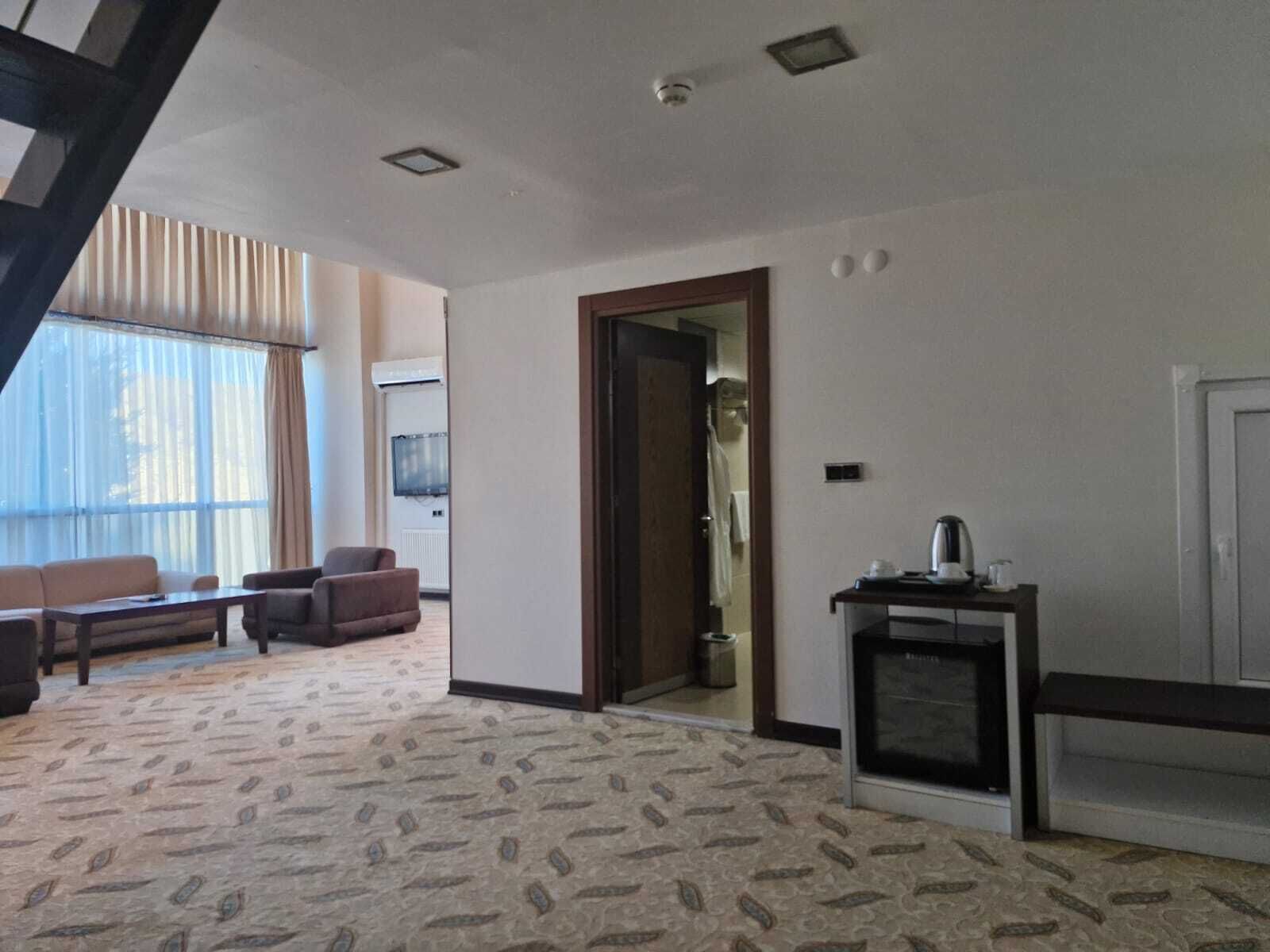 A spacious living room with a patterned carpet, a sofa set, a coffee table, and a fireplace.