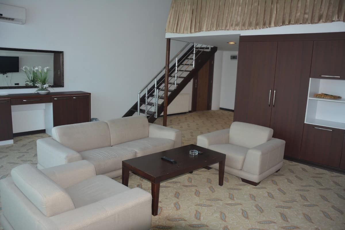 A living room with a sofa set, a coffee table, and a TV on a stand. There is a staircase leading to an upper level.