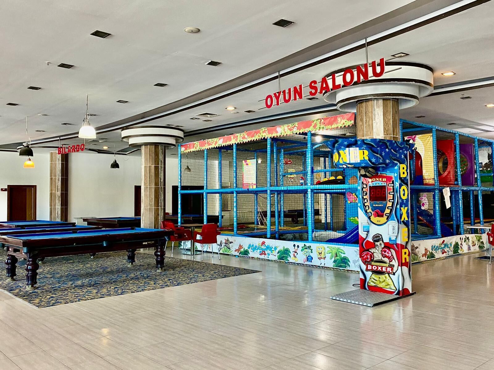 A billiards room with a pool table, a boxing game machine, and a colorful play area.