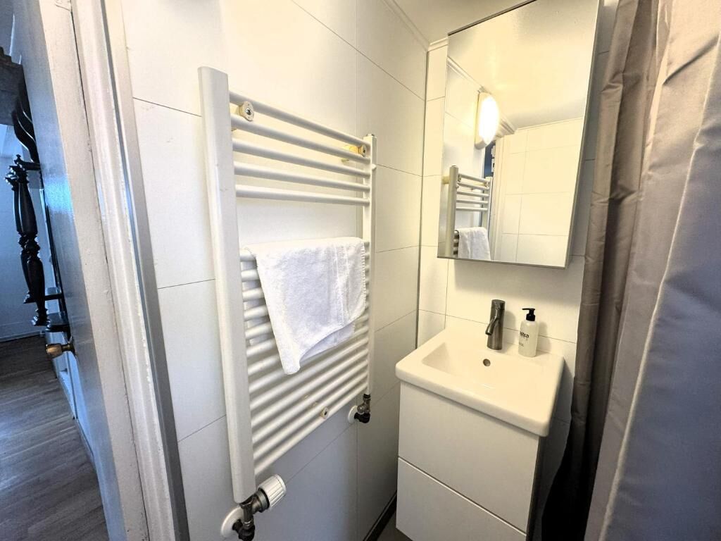 A bathroom with a white towel on a radiator, a sink, and a mirror.