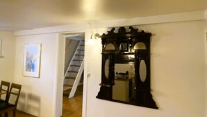 A room with a wooden floor, a white door, a framed picture on the wall, and a staircase leading to another room.