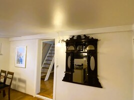 A room with a wooden floor, a white door, a framed picture on the wall, and a staircase leading to another room.