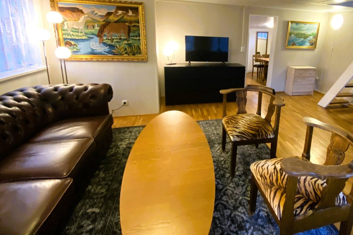 Una sala de estar con un sofá de cuero, una mesa de centro de madera, un televisor de pantalla plana y un cuadro en la pared.
