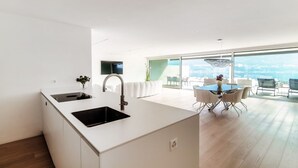 A modern kitchen with a large island, a dining area with a table and chairs, and a view of the city through large windows.