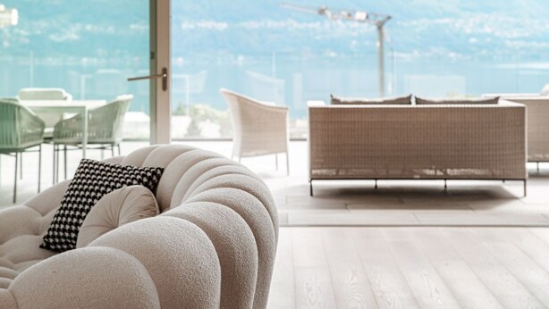 A modern living room with a sofa, chairs, and a view of the cityscape.