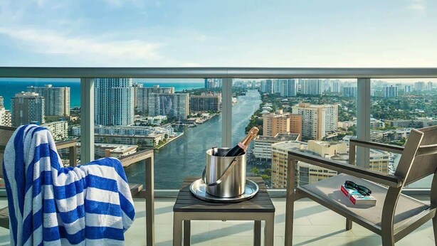 Un balcón con vistas a un paisaje urbano, una botella de champán y una toalla a rayas.