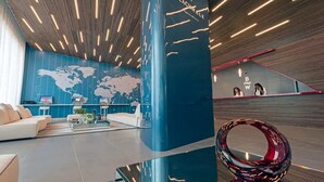 Un vestíbulo moderno con un mapa mundial en la pared, un mostrador de recepción y una zona de estar con una mesa de centro de cristal.